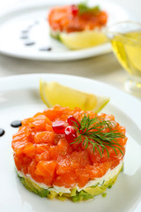 Fresh tartar with salmon, avocado, lemon and soy sauce on white plate, close up