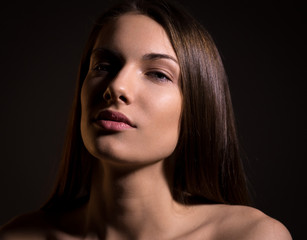 Fototapeta premium Portrait of beautiful brunette woman with natural look and without makeup on black background
