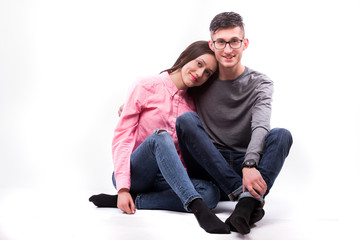 Young hipster man in glasses and woman sitting down and look at camera isolated on the blank white background