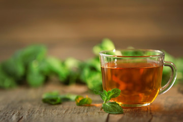 Cup of tea with mint on wooden table
