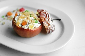 Baked apple with cottage cheese, raisins, candied fruit and nuts on white plate
