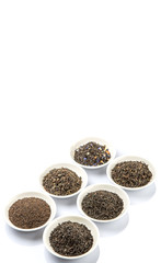 Dried variety of black tea leaves in white bowl over white background