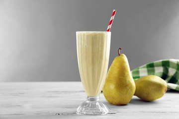 Glass of milk cocktail with pear on grey background