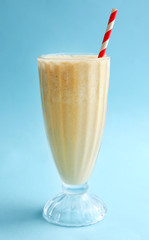 Glass of milk cocktail on blue background
