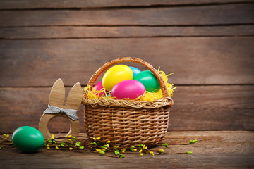 Easter eggs in wicker basket on wooden background