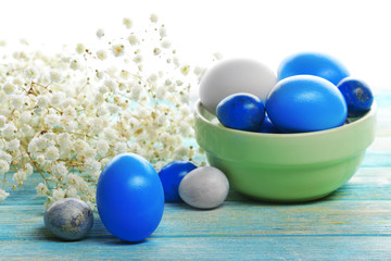 Blue and white Easter eggs with flowers on wooden table closeup