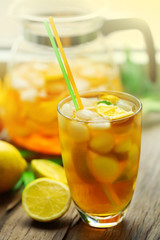 Glass and jar of iced tea with lemon on a windowsill
