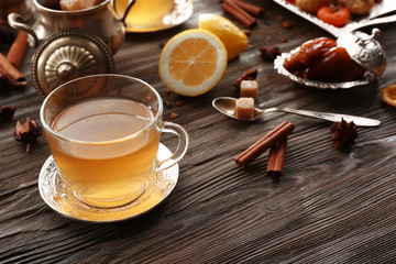Cup of brewed tea with lemon, eastern sweets and spices on wooden table
