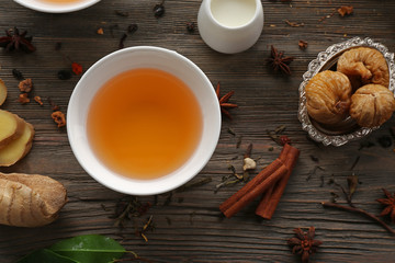 Two cups of brewed tea with ginger and spices on wooden table