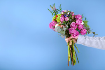 Female hand holding a bouquet of roses on blue background