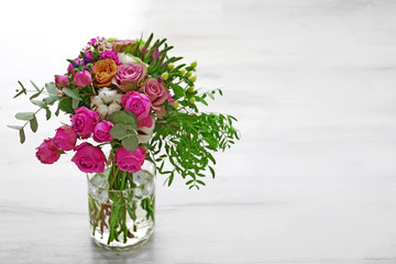 Bouquet of flowers in jar on wooden background