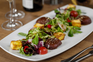meat with croutons, cherry tomatoes, basil, leaves Korn, radishes, peppers and red cabbage with soy sauce on a white plate