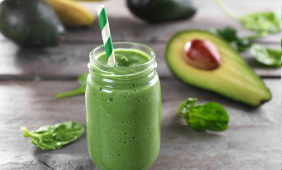 Fresh avocado smoothie with slices on wooden background