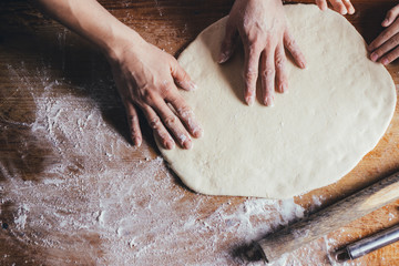 Woman hands kneading dough on the table - obrazy, fototapety, plakaty