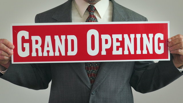 4K: Businessman Holds Up Grand Opening Sign