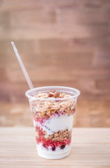 yogurt with granola,honey, almond and fresh berries on wooden board