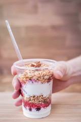 Man hand picking up his healthy granola breakfast with strawberries and yoghurt