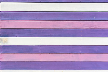 Section of weathered purple, pink and white wood panelling from a beach hut, suitable for backgrounds of beach, seaside and summer holiday themes.