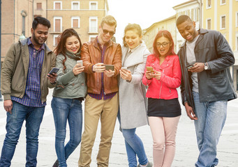 Fototapeta premium Group of young multiracial friends using smartphones on city contest