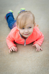Fototapeta premium Happy toddler girl lying on her stomach looking off into the distance.