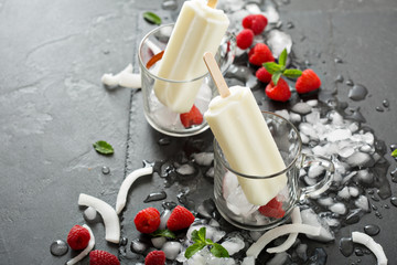 Coconut popsicles with raspberries on black background