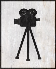 vintage movie camera with tripod on wood grain texture