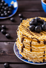 Wafers with chocolate sauce and blueberry on dark wooden background 