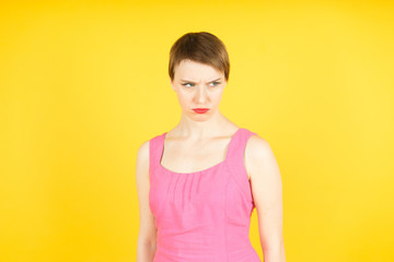 thoughtful young woman looking at something. Colorful studio portrait on yellow background