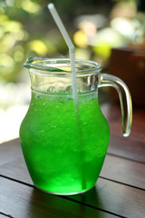 Green Soft drink with ice on wood table and blurred bokeh backgr