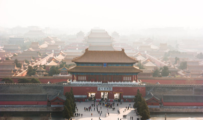 An aerial bird view of the the famous Forbidden City in Beijing, China. The vast area of the architectural complex is covered with evening mist.