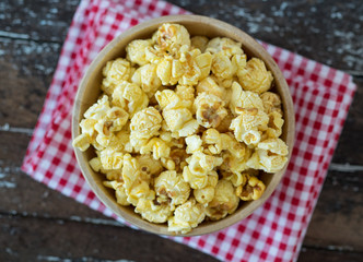popcorn in brown bowl on dark wooden table.