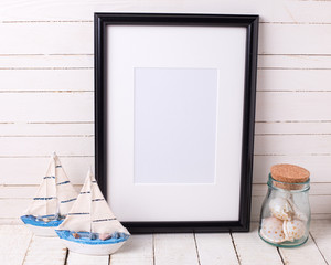 Black empty frame and  ocean theme decorations on white wooden b