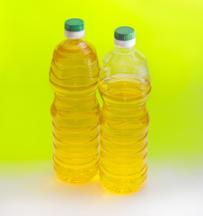 Two bottles of sunflower oil on an yellow background
