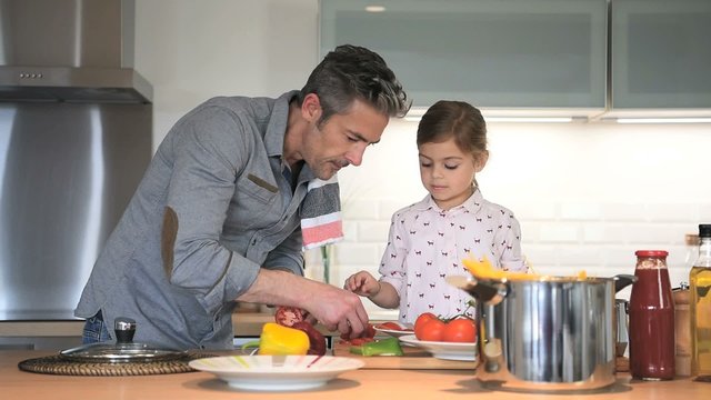Father with little girl cooking together in kitchen