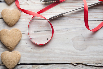 cookies and heart shaped red ribbon on the wooden background