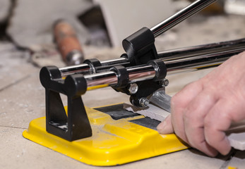 Worker man cuts the ceramic tile