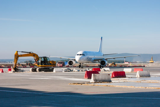 Fototapeta Aircraft maneuvering between excavators and bulldozers