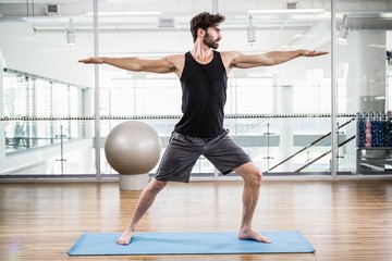 Handsome man doing yoga on mat