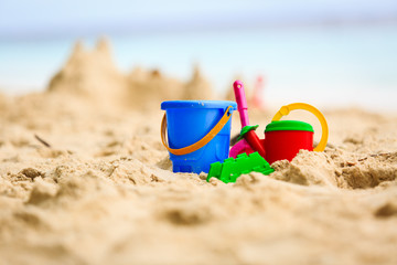 Sand castle on tropical beach and kids toys