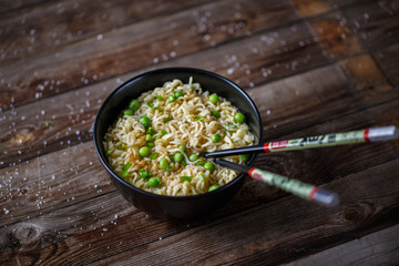 Bowl of noodles with fresh peas and chopped onion.