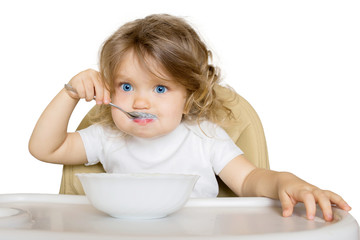 Baby eating baby food in high chair.