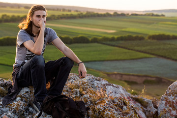 Handsome young man sitting on a rocks.