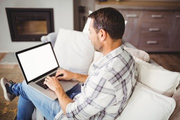 Fototapeta na wymiar Man working on laptop while sitting on sofa