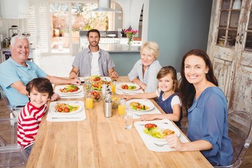 Smiling family with grandparents sitting at dining table