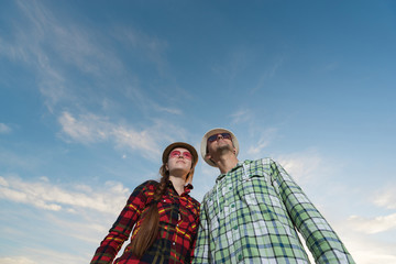 Happy Couple in hat and sunglasses on the sky background.