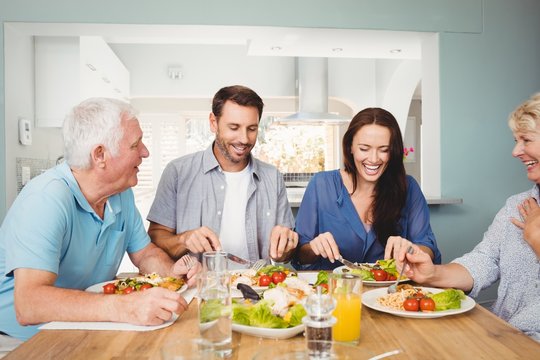 Family laughing while sitting at dining table