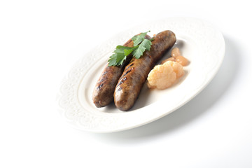 Two meat sausages on a plate on a white background
