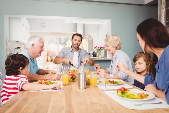 Happy family with grandparents sitting at dining table