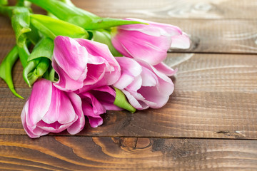 Obraz na płótnie Canvas beautiful pink tulips lying on the burlap on the background of old brown boards. The idea of Mother's day cards, March 8, birthday with free space for your text