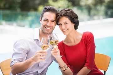 Portrait of smiling couple toasting white wine 